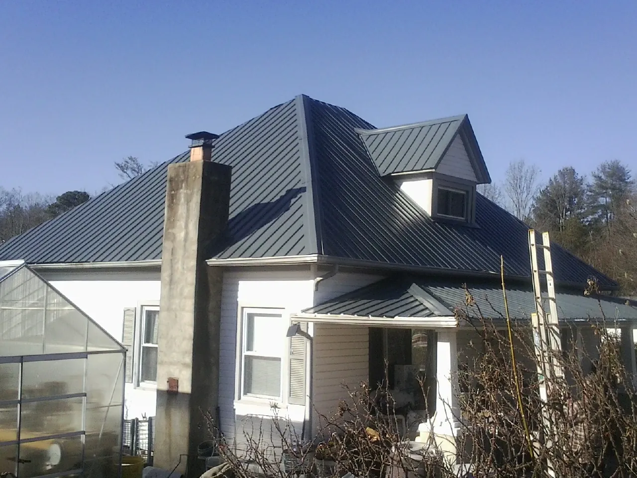 Dark blue standing seam metal roof on a white farmhouse with dormer — Slate & Tile Roof Repair by Roofing Brothers in Normandy