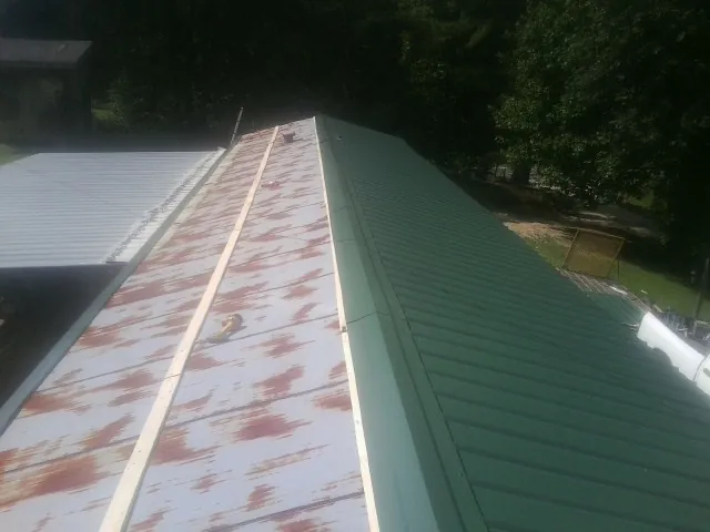 Old rusted panels beside newly installed green metal roofing — Wind Damage Roof Repair by Roofing Brothers in Normandy