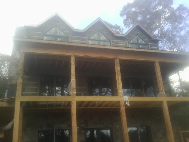 Dormers and porch framing on a large log home under construction — Roof Coating work by our crew in Normandy