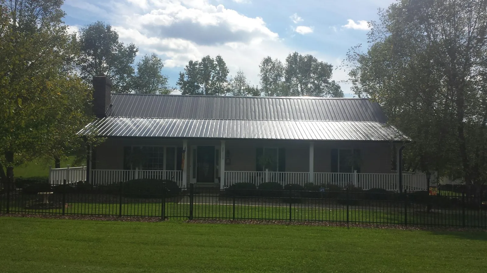 Gray metal roof on a brick ranch with a full width front porch — Gutter Guard Installation work by our crew in Normandy