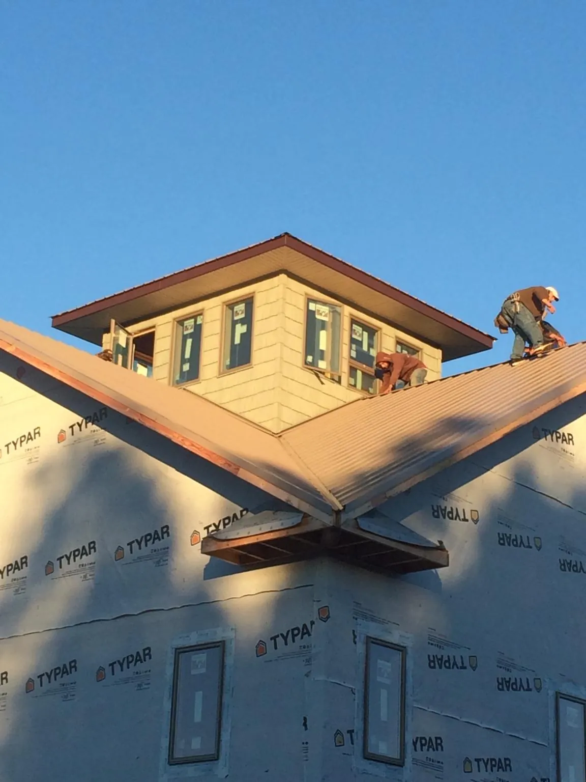 Roofers working around a rooftop cupola on a new metal roof at sunset — Roof Waterproofing in Normandy by Roofing Brothers